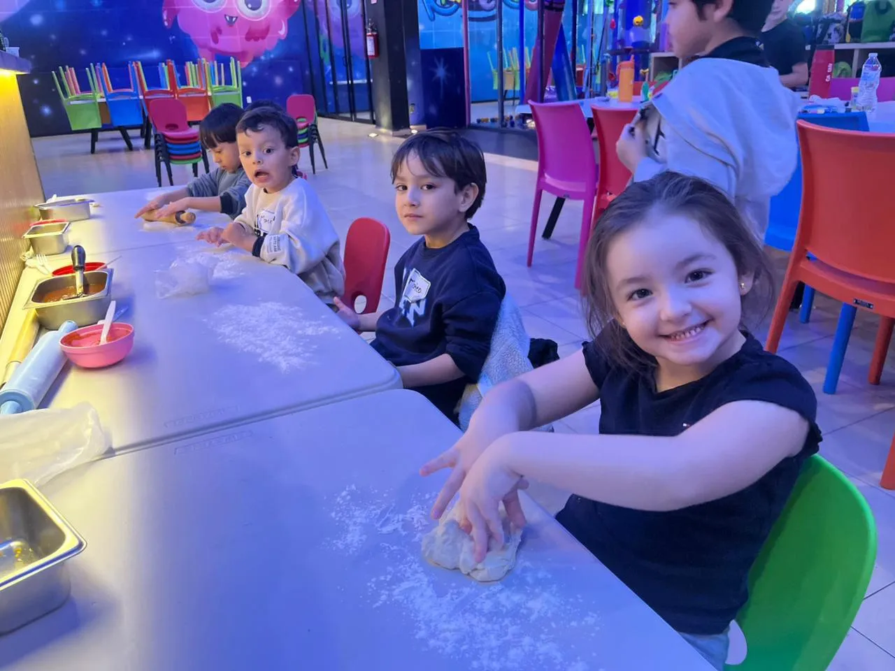 Niña sonriendo mientras amasa en la clase de cocina del campamento Kidiverso