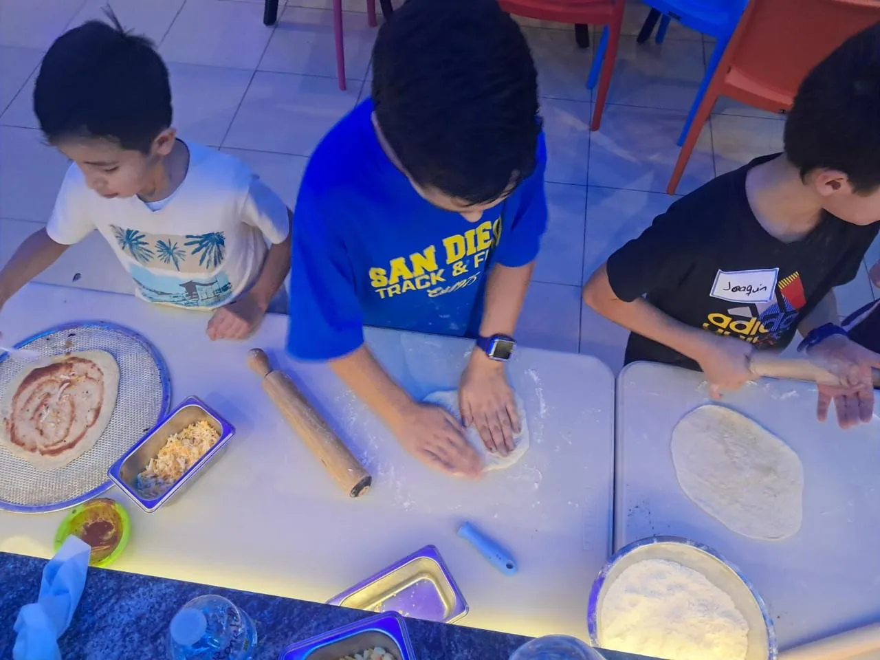 Niños haciendo pizza en la clase de cocina del campamento